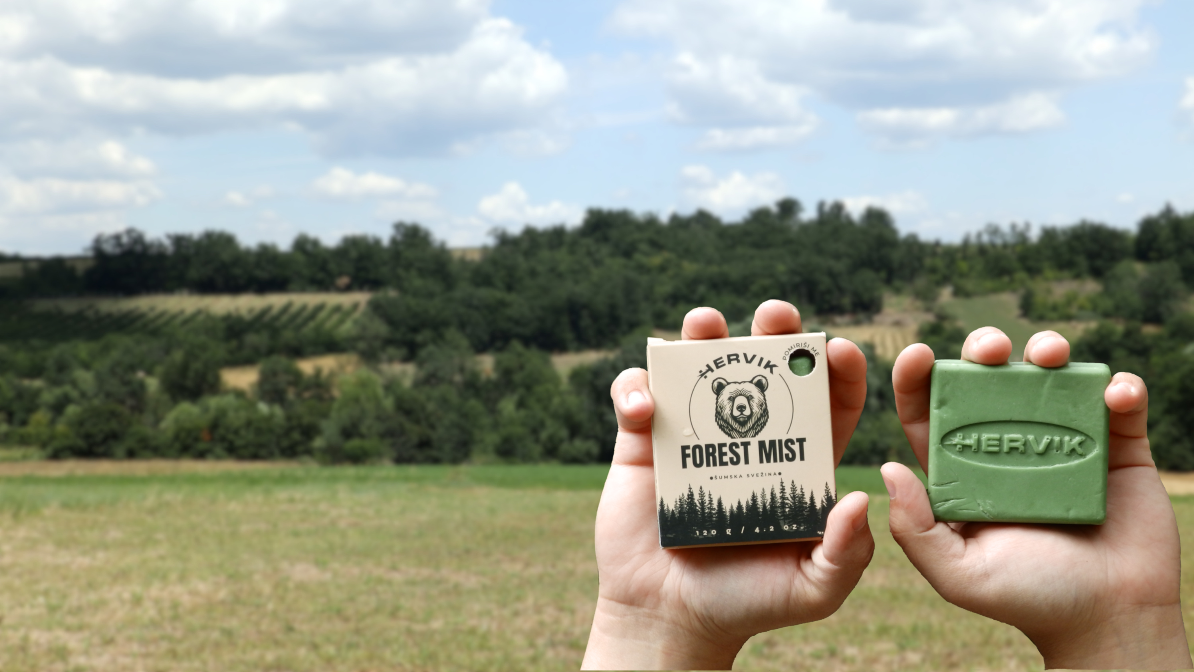 Ruke drže Hervik Forest Mist prirodni sapun i kutiju u prirodi