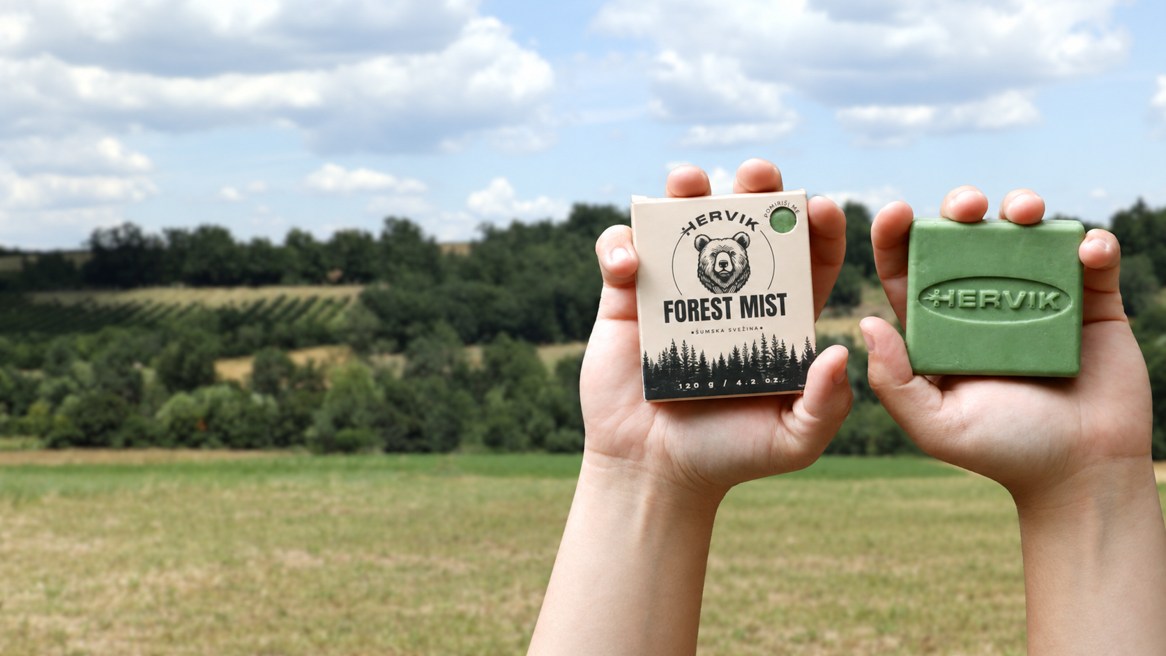 Ruke drže Hervik Forest Mist prirodni sapun i kutiju u prirodi